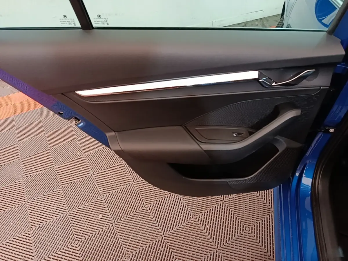 Vue rapprochée de la porte avant gauche d'une Skoda Octavia bleu 2022, avec garniture noire et poignée chromée.