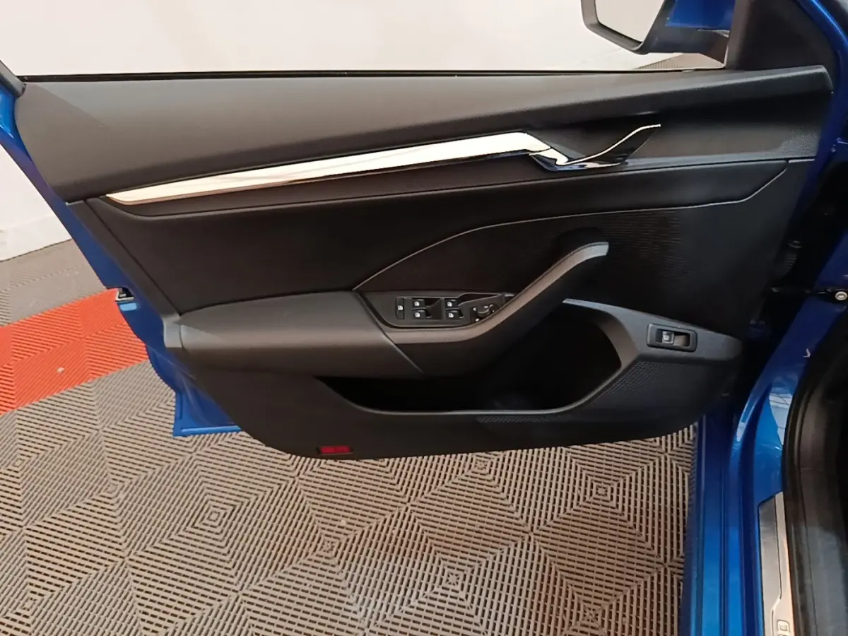 Vue intérieure de la porte avant gauche bleue d’une Skoda Octavia 1.4 TSI PHEV avec commandes électriques et garniture noire.