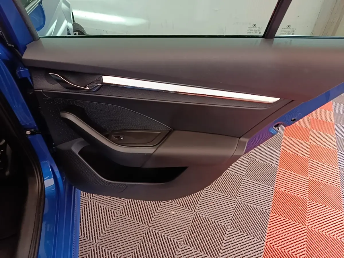 Vue rapprochée de la porte arrière gauche bleu vif d’une Skoda Octavia 2022, avec garniture noire et poignée intégrée.