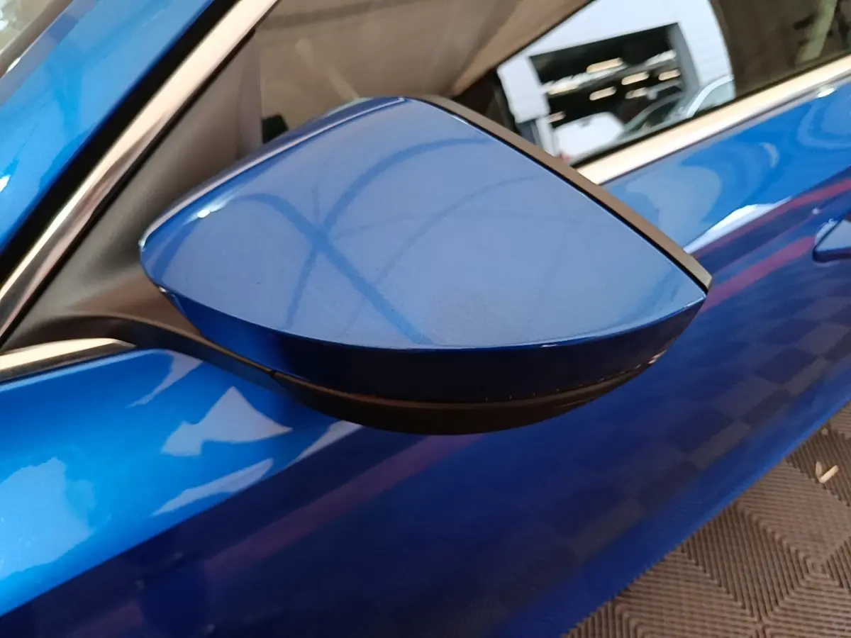 Rétroviseur côté conducteur bleu de la Skoda Octavia 1.4 TSI PHEV iV 2022, vue rapprochée sur la carrosserie brillante.
