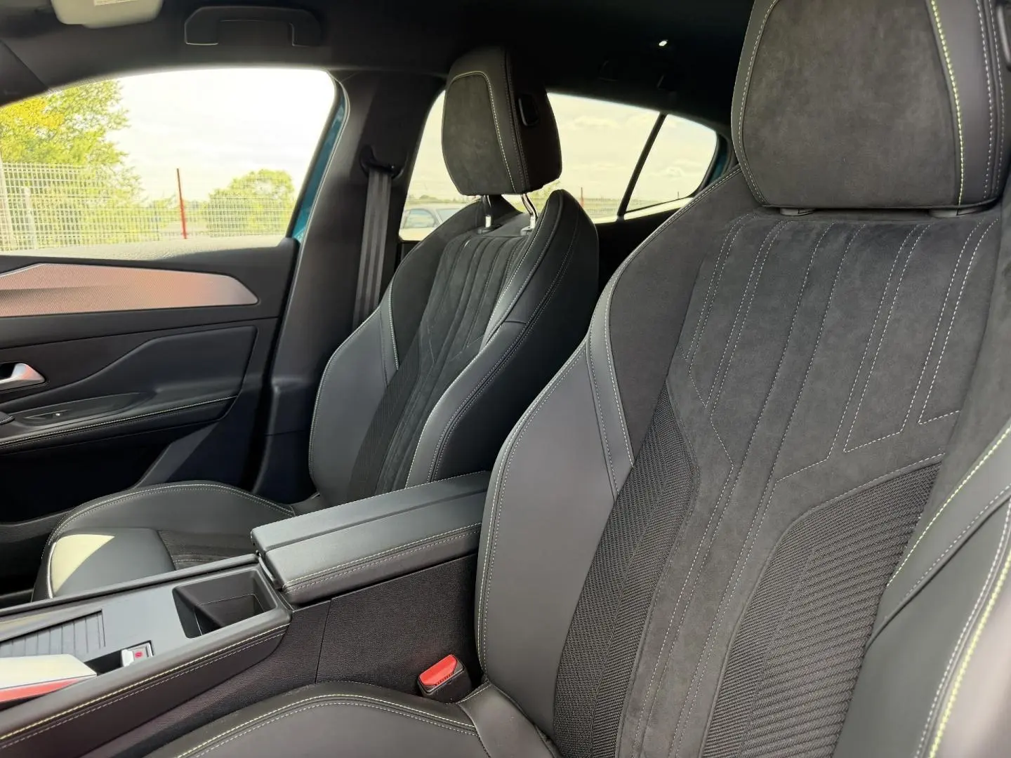 Vue intérieure côté droit des sièges avant en tri-matières noires avec surpiqûres contrastantes sur Peugeot 408 Hybrid 2025.