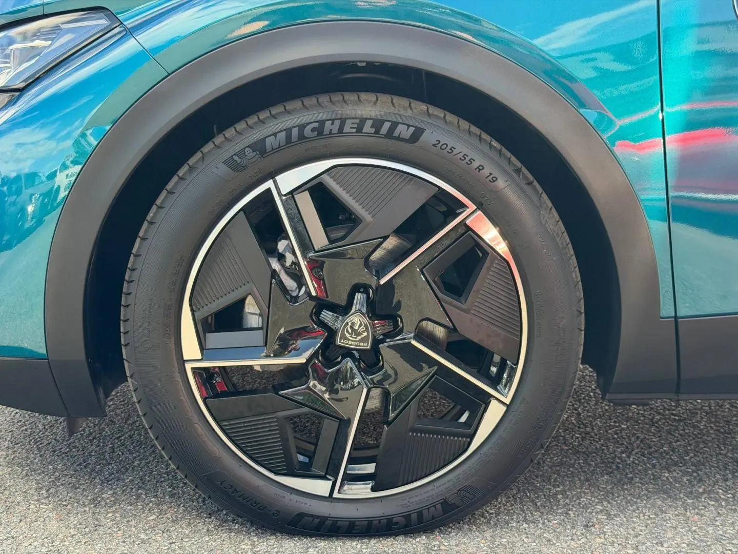 Gros plan sur la roue avant gauche avec jante alu noire et argentée du Peugeot 408 Hybrid Bleu Obsession.