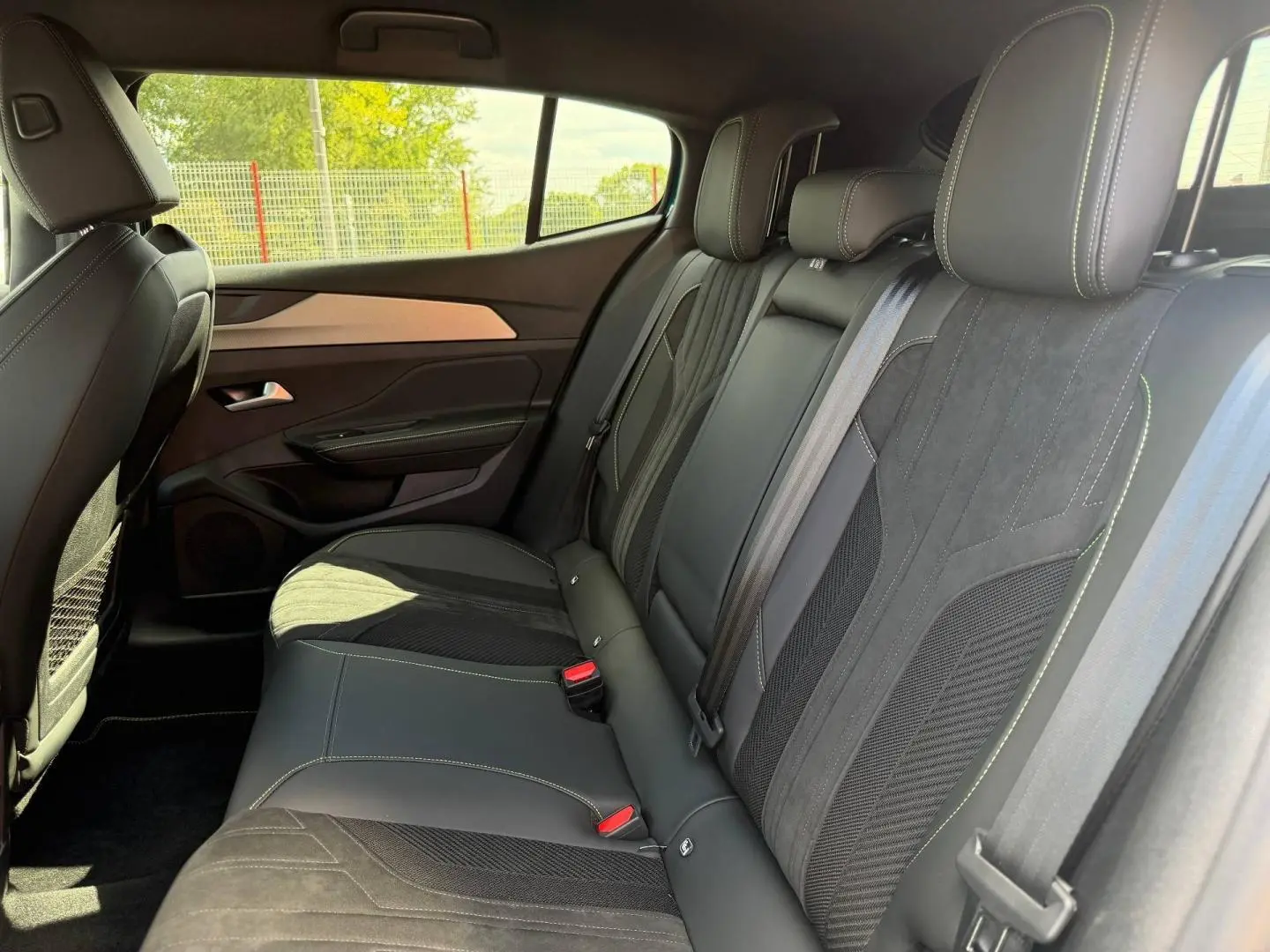 Vue intérieure côté droit des sièges arrière en cuir et tissu noir avec surpiqûres contrastantes du Peugeot 408 Hybrid 2025.