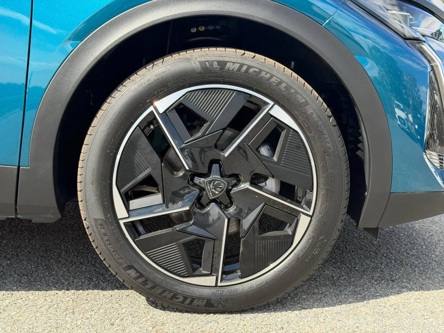 Gros plan sur la roue avant droite avec jante alu noire et argentée du Peugeot 408 Hybrid Bleu Obsession.