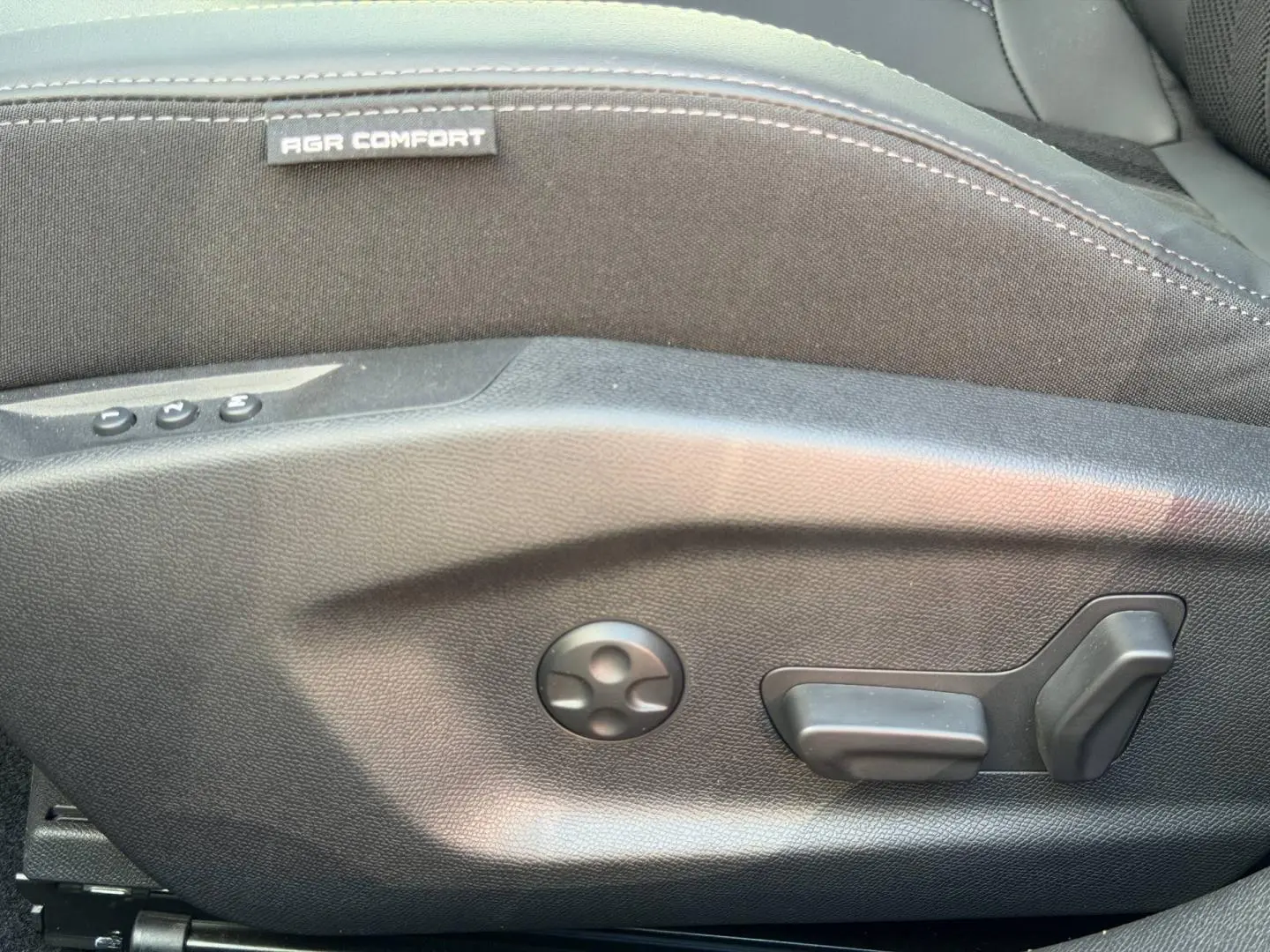 Détail des commandes de réglage électrique du siège conducteur noir de la Peugeot 408 Hybrid 145ch GT.