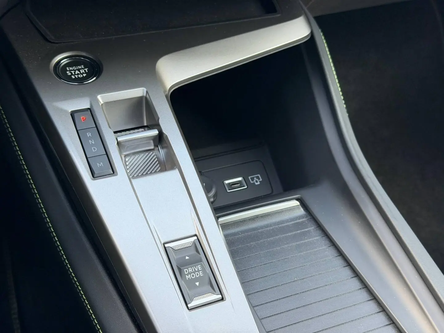 Vue rapprochée de la console centrale argentée avec sélecteur de mode de conduite et bouton start du Peugeot 408 Hybrid 2025.