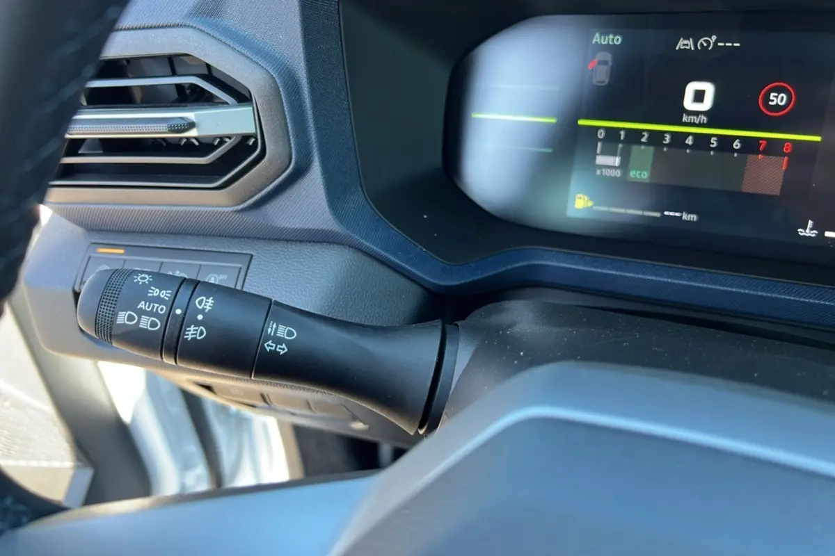 Détail du commodo des phares et tableau de bord numérique du Dacia Bigster blanc glacier 2025, version TCE 130 4X4.