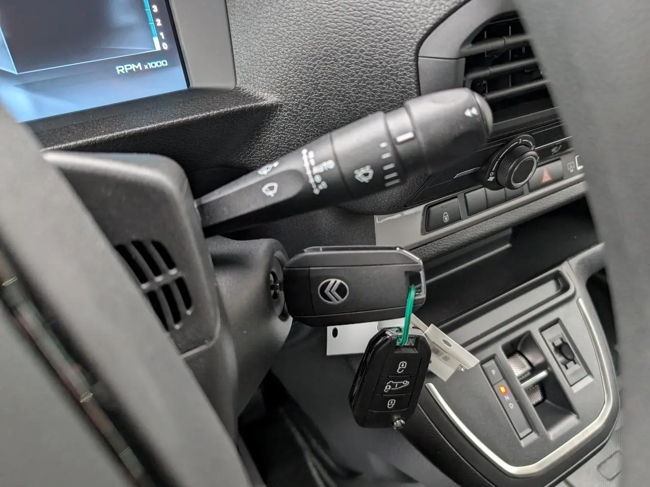 Gros plan sur le contacteur et clé du tableau de bord du Citroën Jumpy gris, avec levier de vitesses automatique visible.