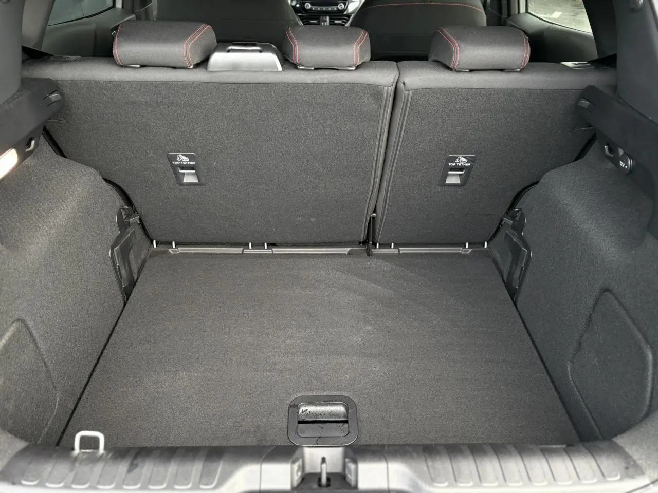 Vue intérieure du coffre spacieux du Ford Puma 2023, avec banquette arrière en tissu gris et surpiqûres rouges visibles.