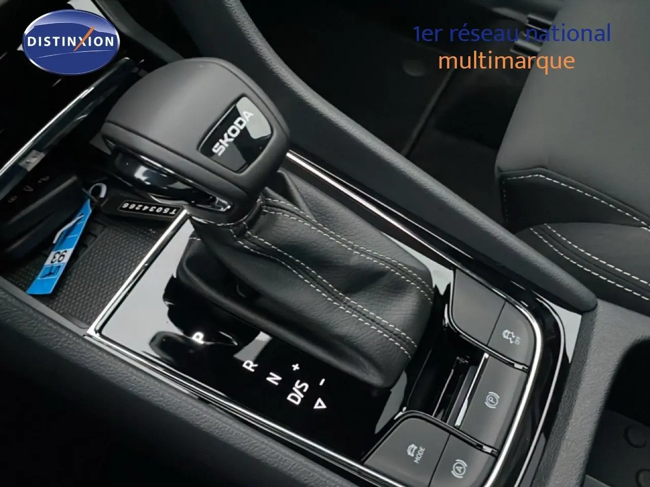 Gros plan sur la commande de boîte automatique noire avec logo SKODA, intérieur cuir gris argent du ŠKODA KAROQ 2025.