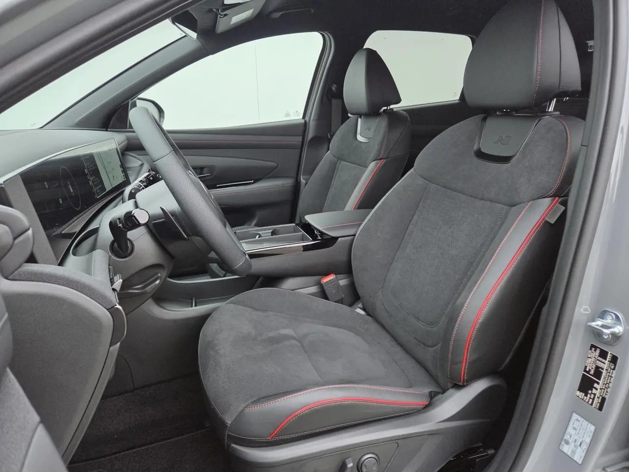 Vue intérieure côté conducteur du Hyundai Tucson 2025 gris Ecotronic, sièges N Line cuir/alcantara avec surpiqûres rouges.