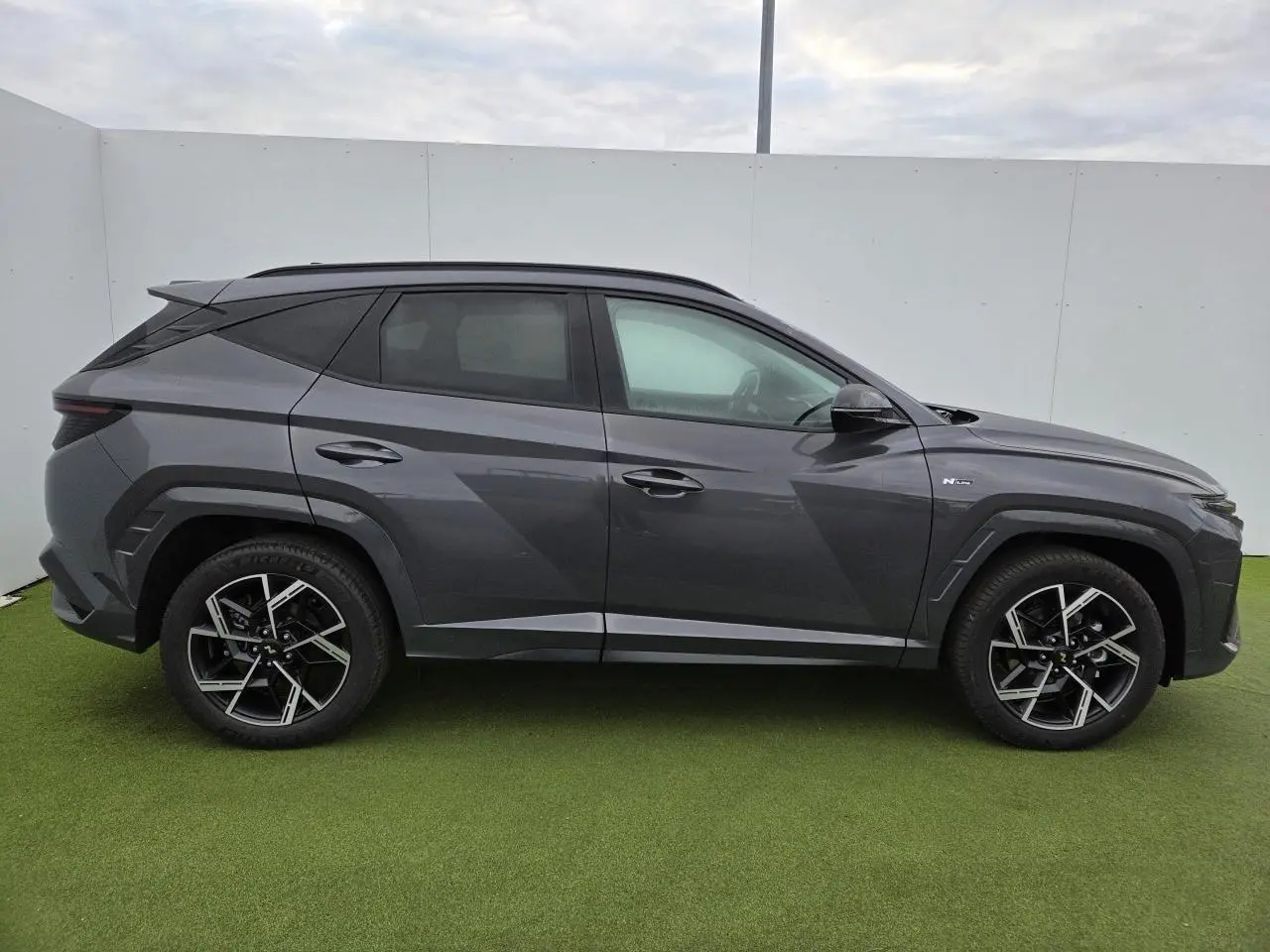 Vue de profil côté gauche du Hyundai Tucson 2025 gris métallisé avec jantes alliage 19'' et finitions N Line.