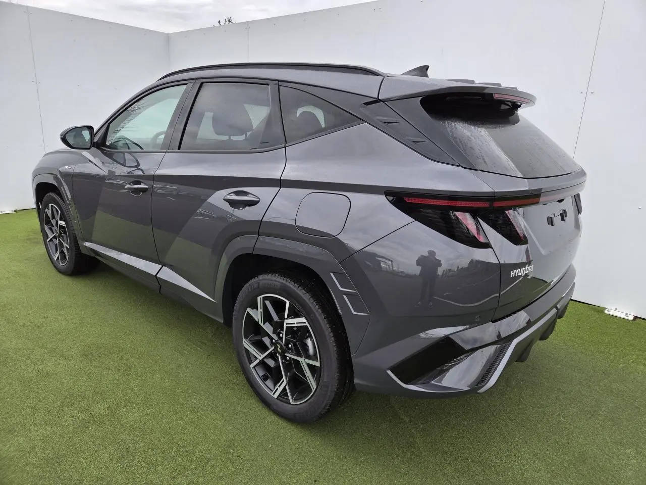 Vue 3/4 arrière droite du Hyundai Tucson 2025 gris métallisé avec jantes alliage et feux arrière à bandeau lumineux.