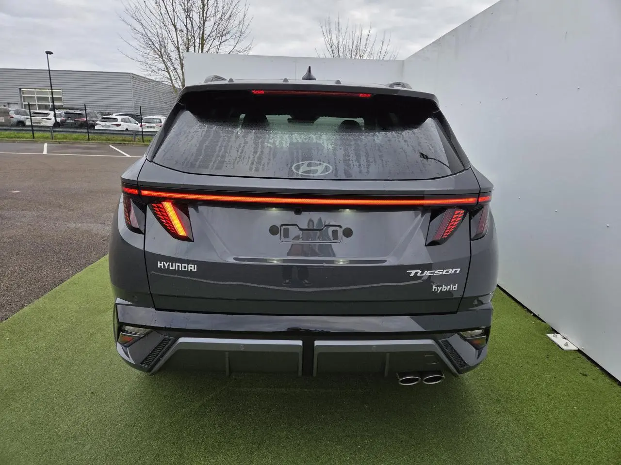 Vue arrière du Hyundai Tucson 2025 gris métallisé avec feux LED allumés et double sortie d’échappement côté droit.