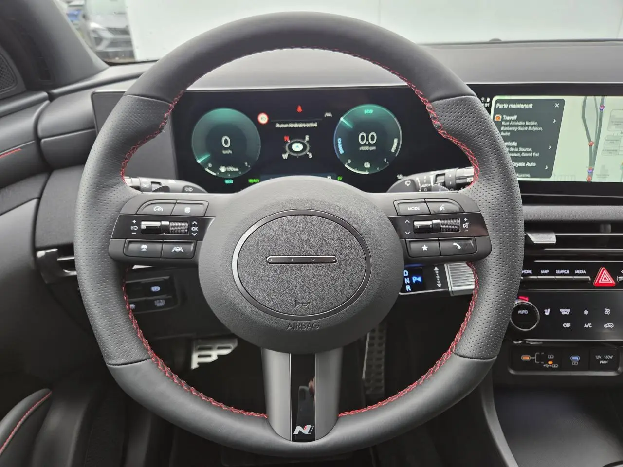 Vue rapprochée du volant sport cuir noir avec surpiqûres rouges et tableau de bord numérique du Hyundai Tucson N Line 2025.