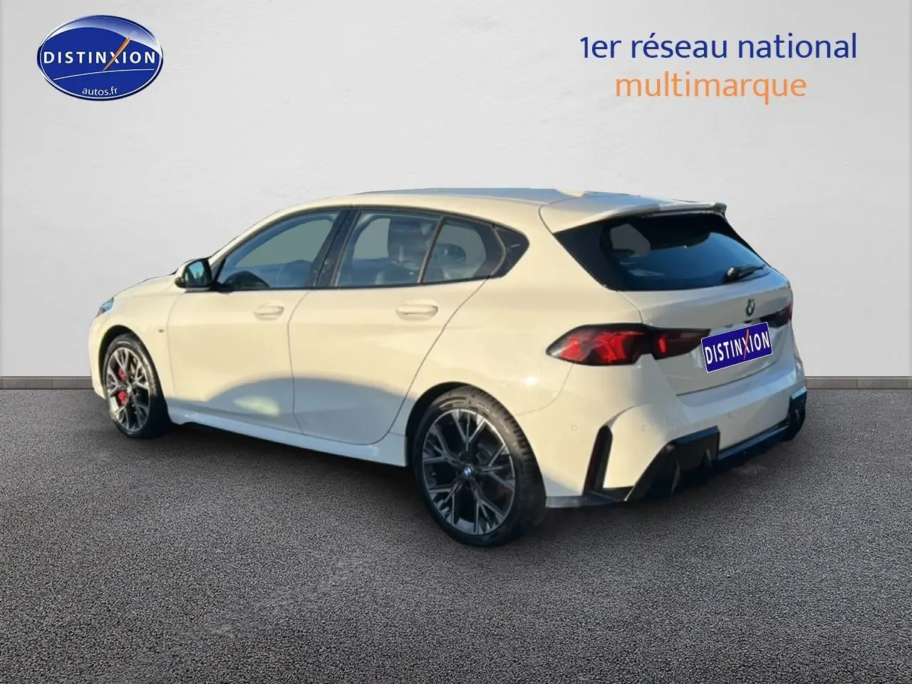 BMW Série 1 blanche alpin vue 3/4 arrière droit, avec jantes 18 pouces bicolores et becquet sportif M Sport Pro.