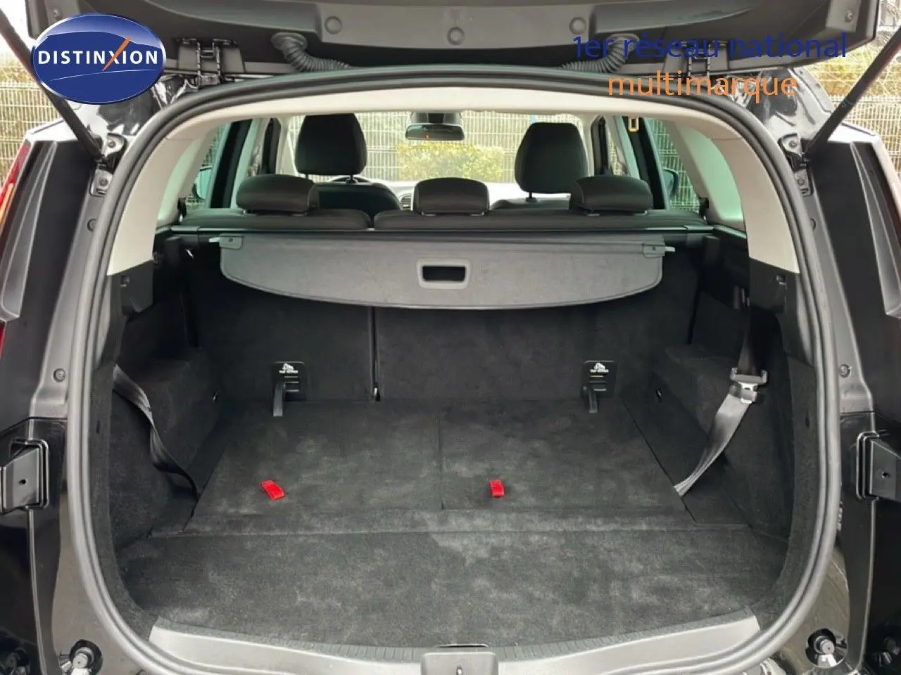Coffre ouvert en vue arrière d’un Renault Grand Scenic noir étoile métal, avec banquette rabattue et cache-bagages visible.