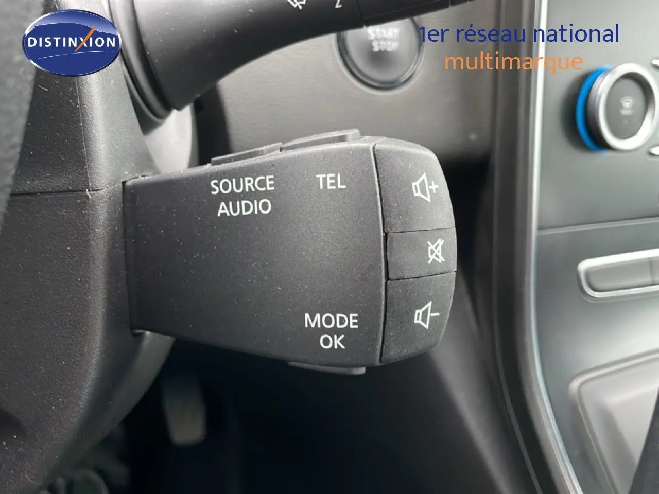 Gros plan sur la commande audio au volant d’un Renault Grand Scenic noir étoile métal, avec bouton mode et volume.
