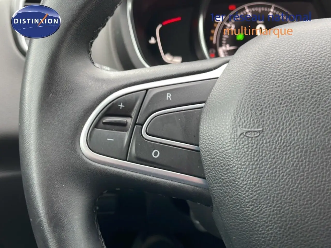 Gros plan sur le volant noir du Renault Grand Scenic 2022, montrant les commandes intégrées à gauche.