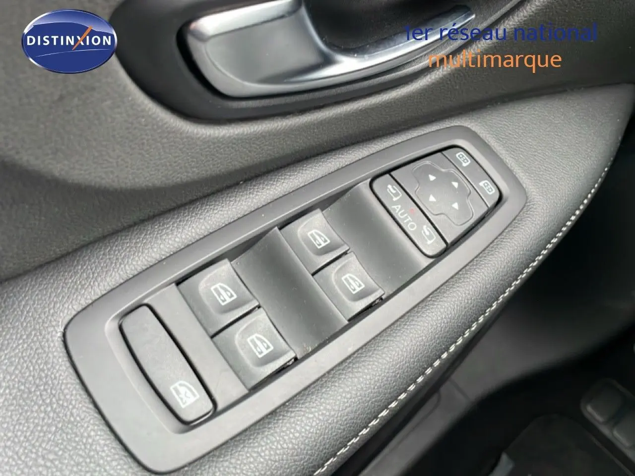 Gros plan sur les commandes de lève-vitres côté conducteur d’un Renault Grand Scénic noir étoile métal, intérieur cuir noir.