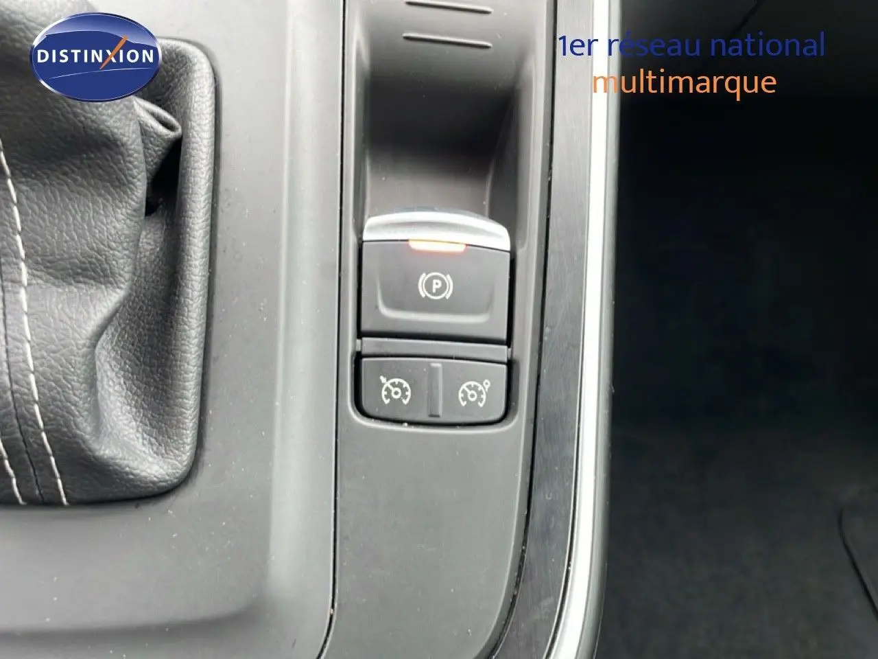 Gros plan sur la console centrale du Renault Grand Scenic noir étoile métal, montrant le frein à main électronique et commandes de régulateur.
