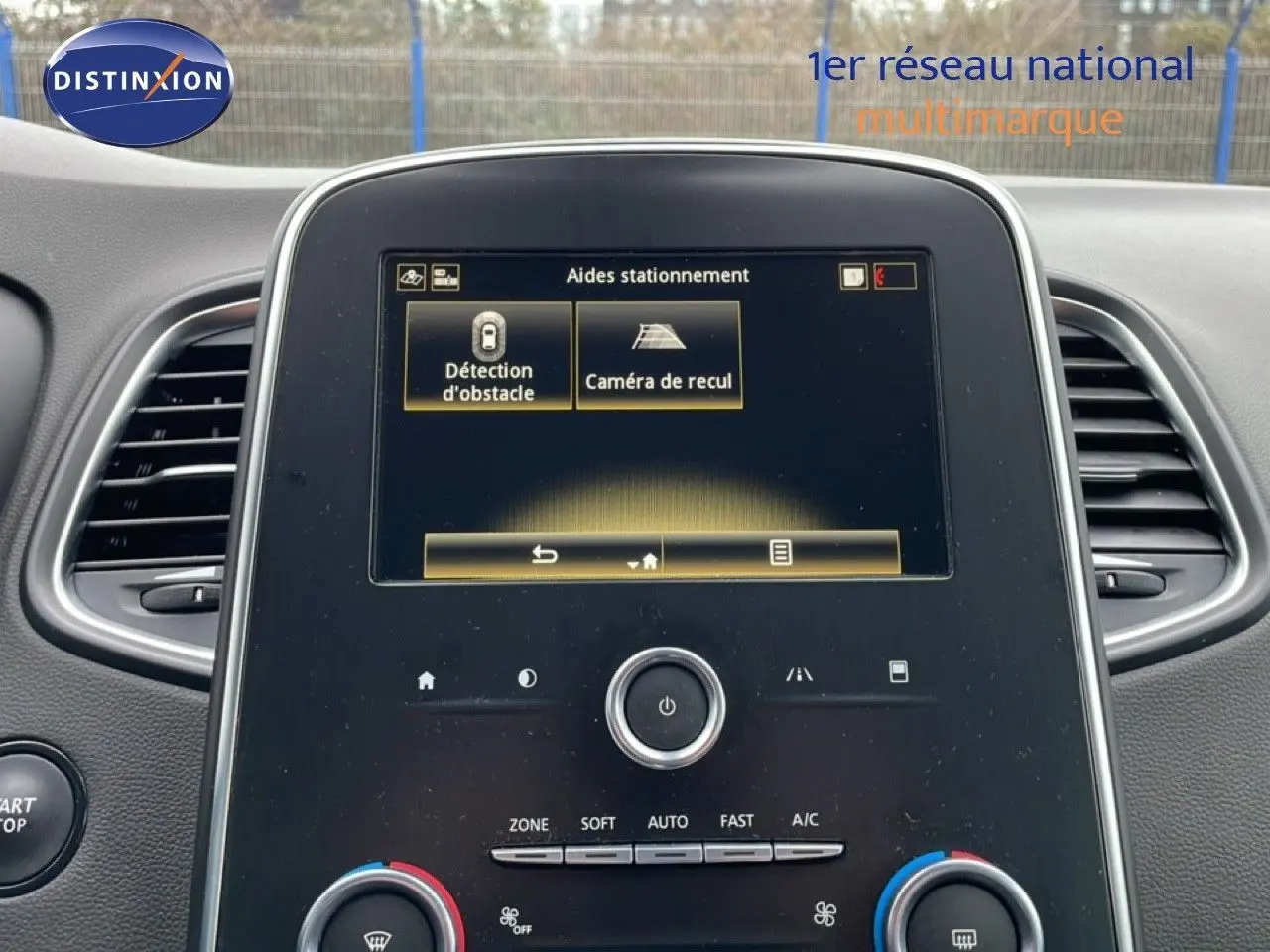 Vue rapprochée du tableau de bord noir du Renault Grand Scenic 2022, écran tactile affichant les aides au stationnement.