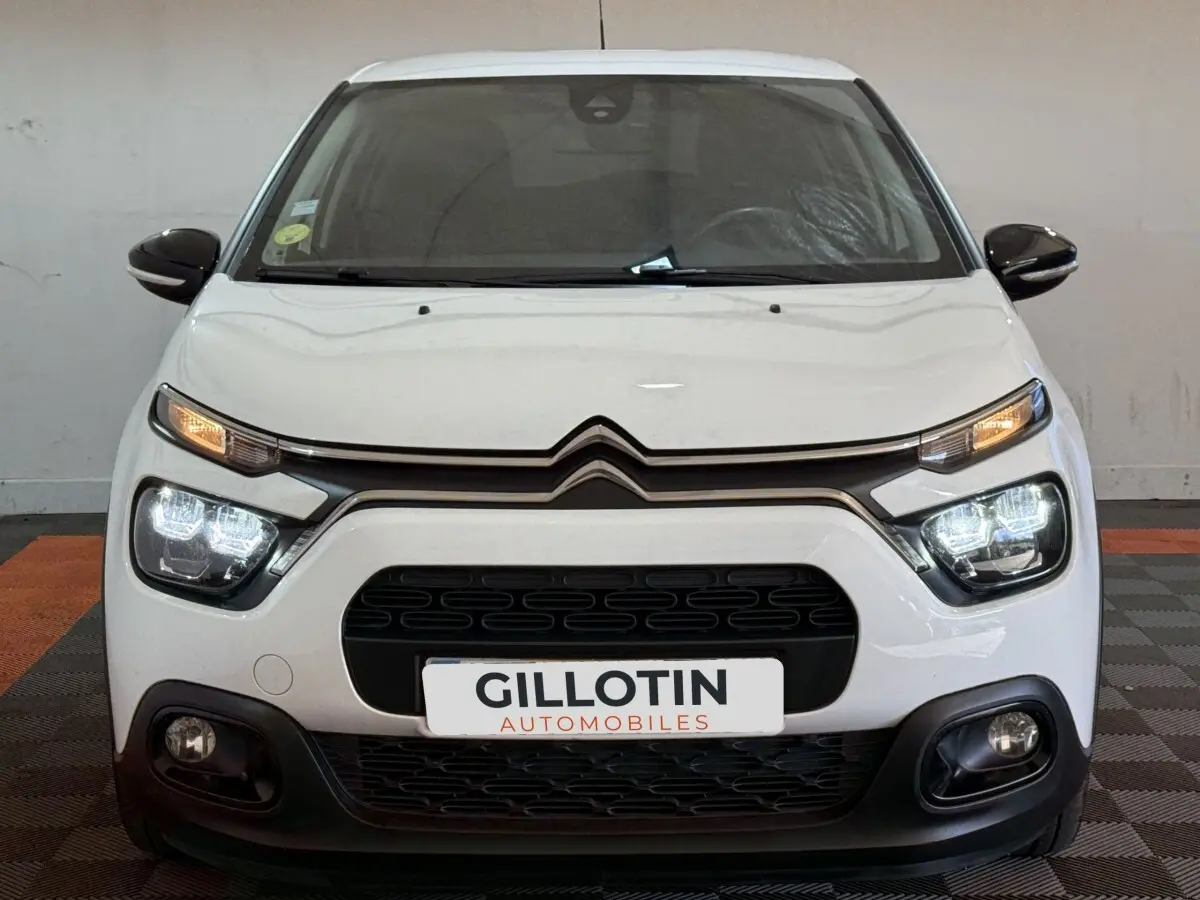 Vue avant d'une Citroën C3 blanche 2021 avec phares LED allumés et calandre noire distinctive.