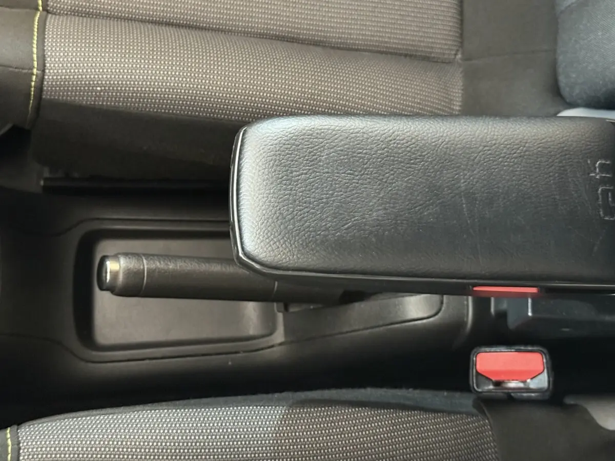 Vue rapprochée de la console centrale intérieure de la Citroën C3 blanche, avec frein à main et accoudoir noir.