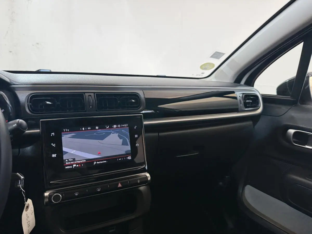 Vue intérieure côté passager du tableau de bord noir et écran tactile de navigation de la Citroën C3 blanche 2021.