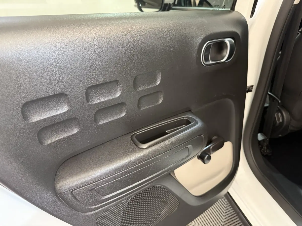 Détail de la porte arrière droite noire avec poignée et manivelle de vitre sur Citroën C3 blanc 2021.