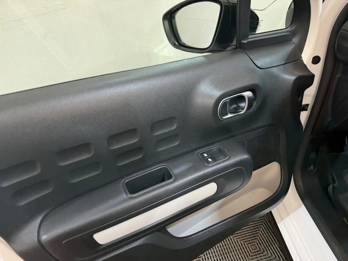 Vue rapprochée de la porte avant droite noire et blanche du Citroën C3 BlueHDi 100 Feel 2021 avec commandes de vitres électriques.