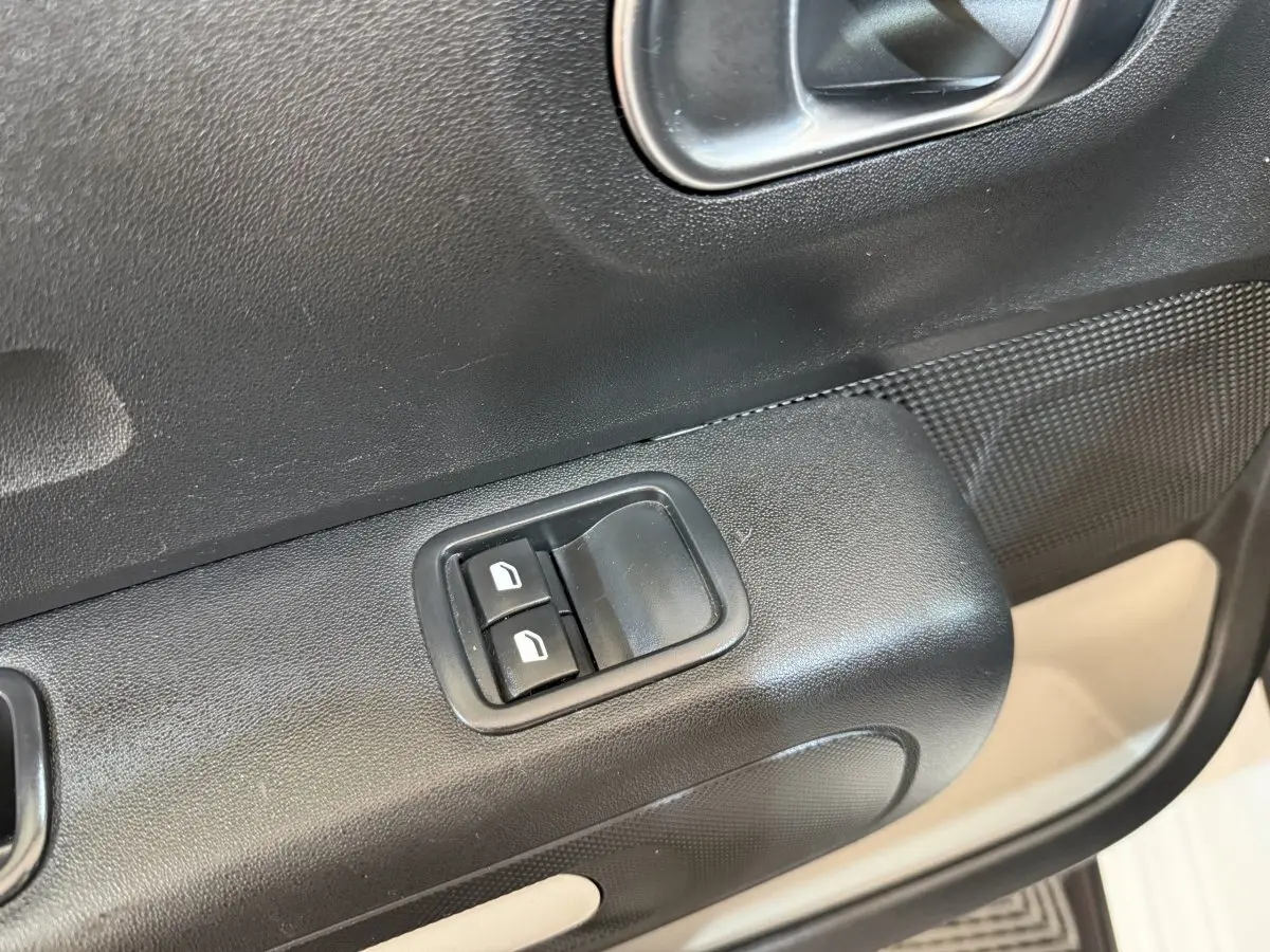 Gros plan sur les commandes des vitres électriques côté conducteur d'une Citroën C3 blanche, intérieur noir.
