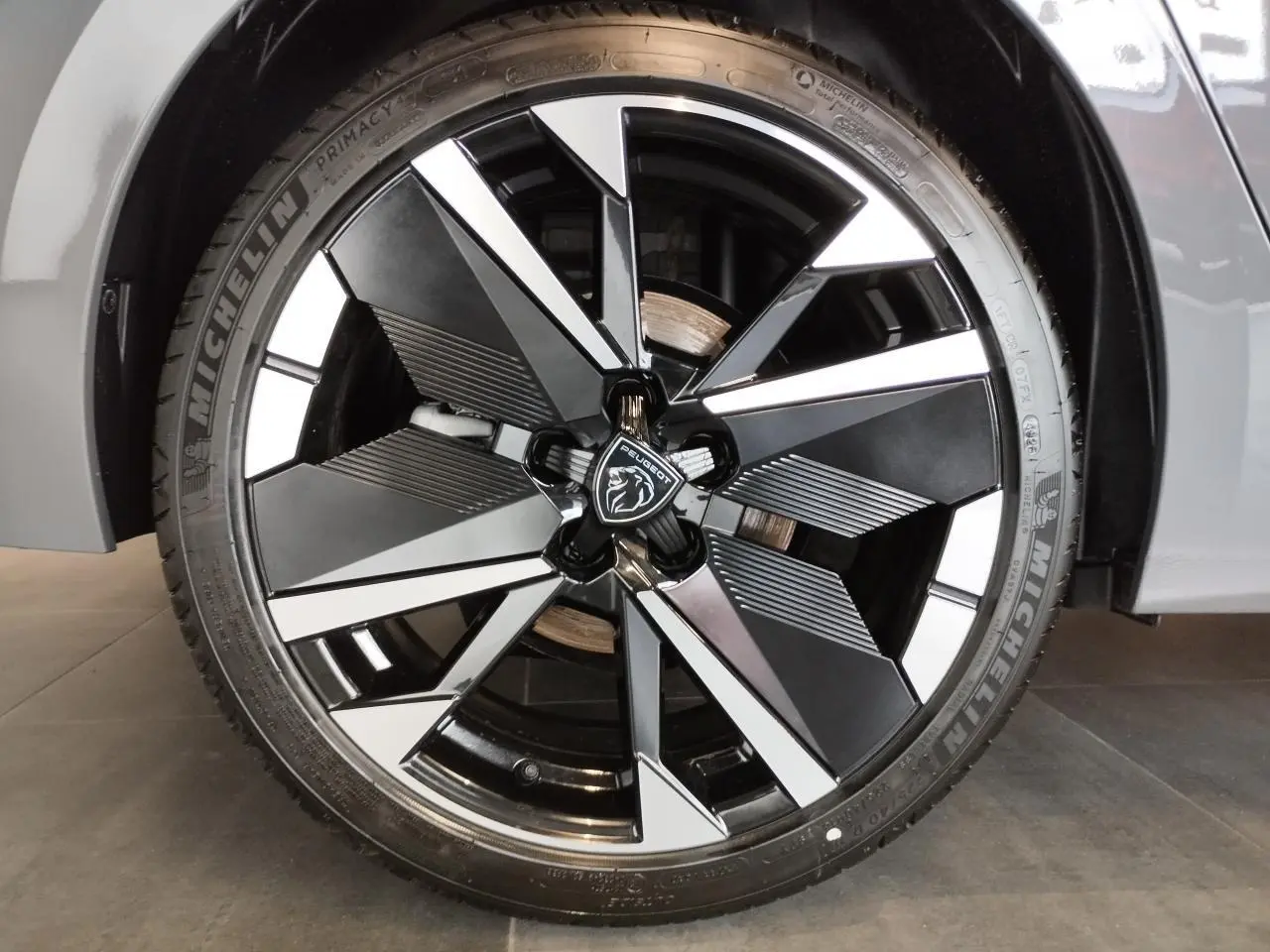 Gros plan sur la jante alliage bi-tons noir et argentée de la Peugeot 308 gris selenium, avec logo central lion.