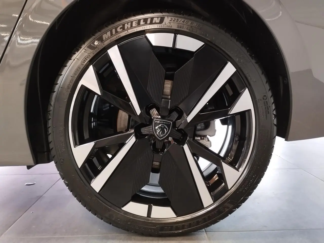 Gros plan sur la jante alliage bi-ton noir et argent avec logo Peugeot sur un pneu Michelin, partie avant droite gris selenium.