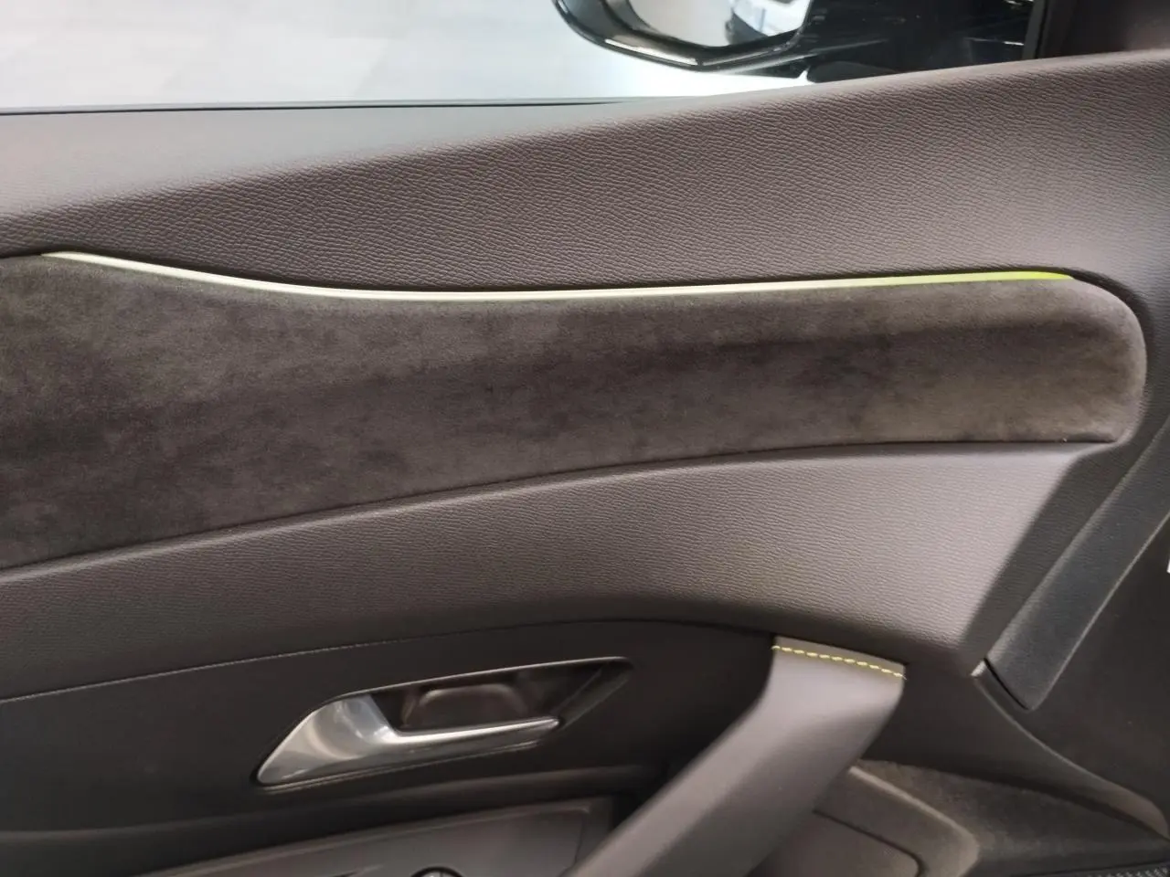 Gros plan sur la garniture intérieure de porte côté droit du Peugeot 308 gris Selenium avec surpiqûres vert Adamite.