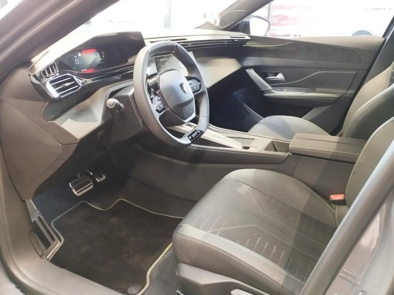 Intérieur avant droit de la Peugeot 308 gris Selenium, volant compact GT cuir et tableau de bord numérique 10 pouces.