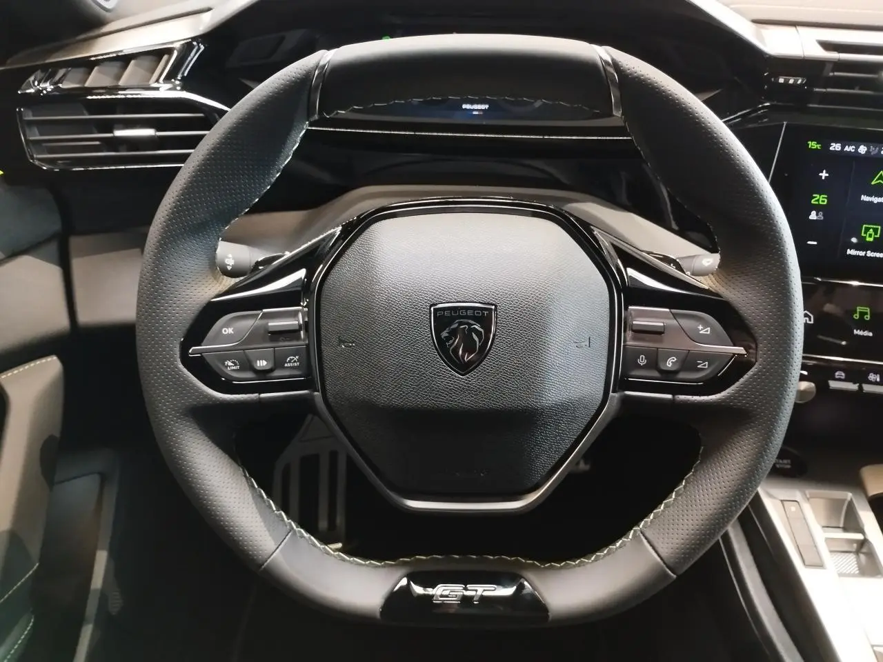 Volant compact GT en cuir noir avec surpiqûres vert Adamite et logo Peugeot au centre, vue de face.