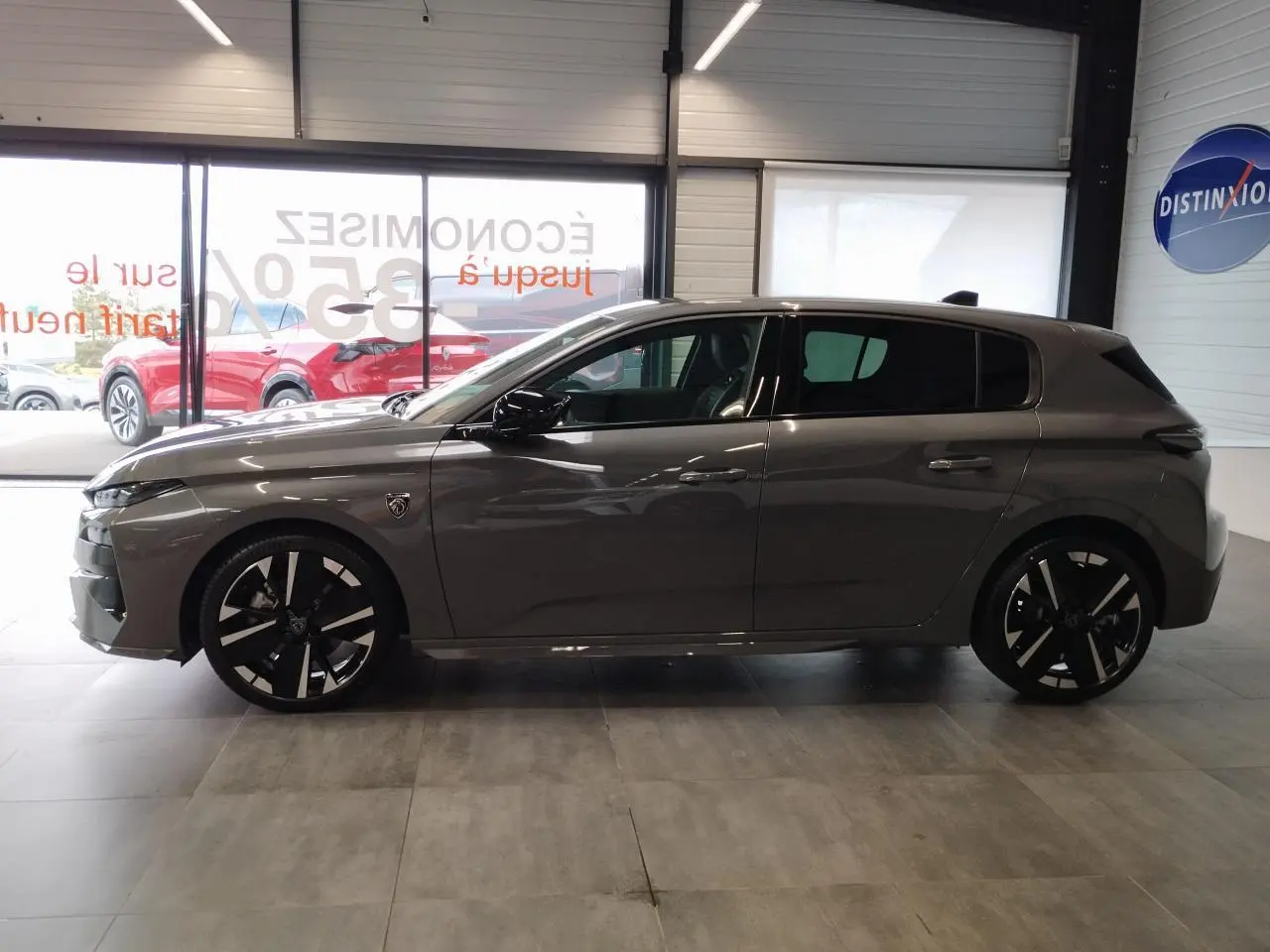 Profil côté gauche de la Peugeot 308 gris selenium 2026 avec jantes alliage 18 pouces et blason distinctif sur aile avant.