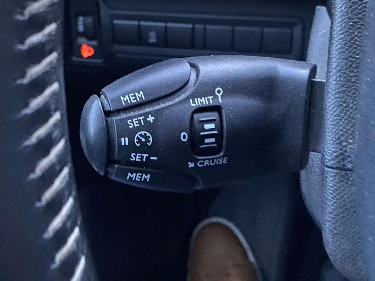 Commande de régulateur de vitesse au volant d'une Peugeot 308 gris clair, vue rapprochée côté gauche.