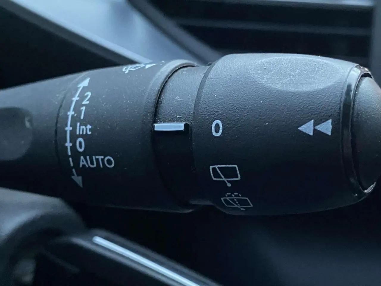 Gros plan sur la commande d'essuie-glace de la Peugeot 308 gris clair, montrant les réglages automatiques et intermittents.