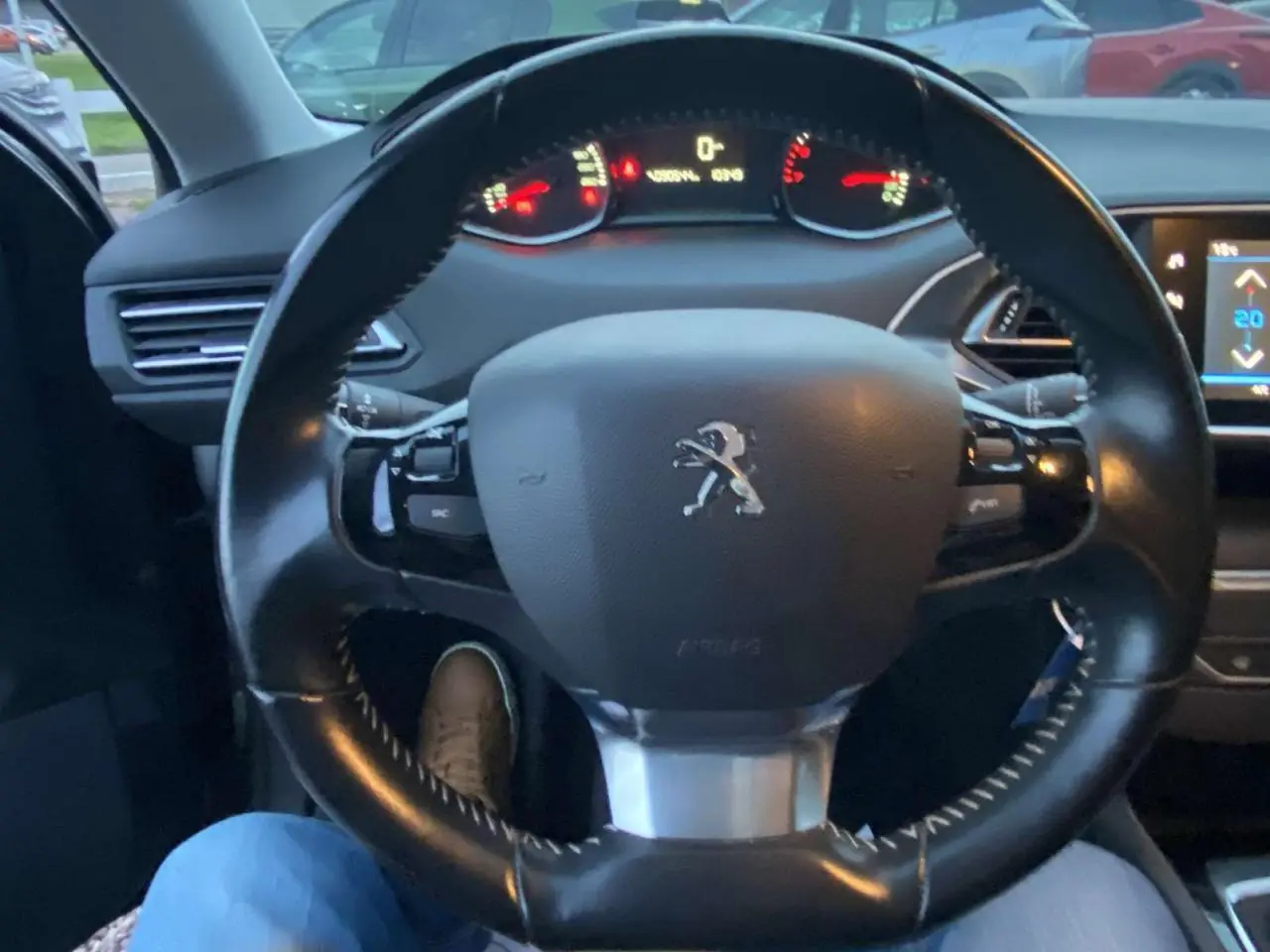 Vue intérieure centrée sur le volant cuir noir du Peugeot 308 2020 avec tableau de bord et écran tactile visible.