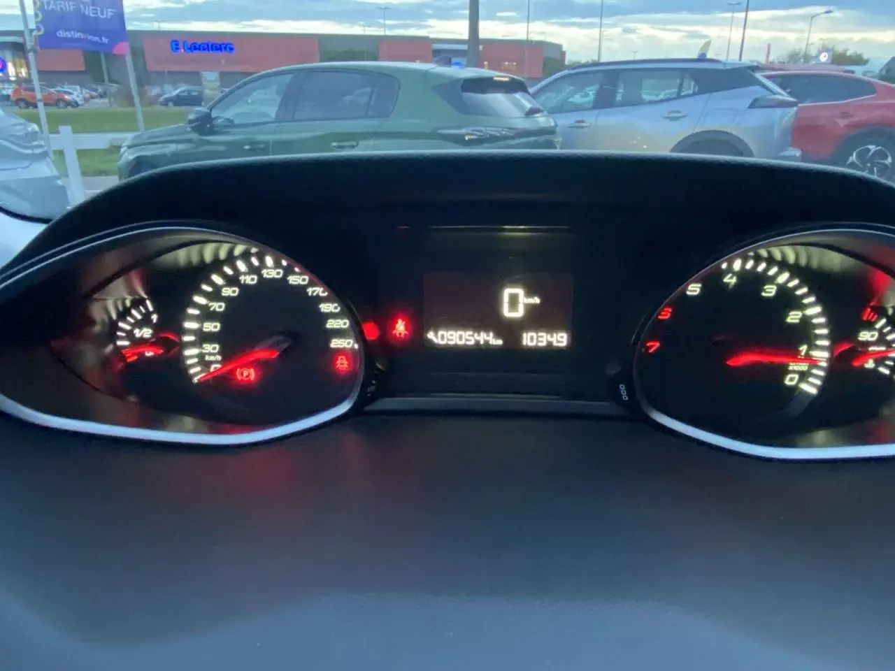 Vue du tableau de bord éclairé d'une Peugeot 308 gris clair, affichant le compteur de vitesse et le compte-tours.