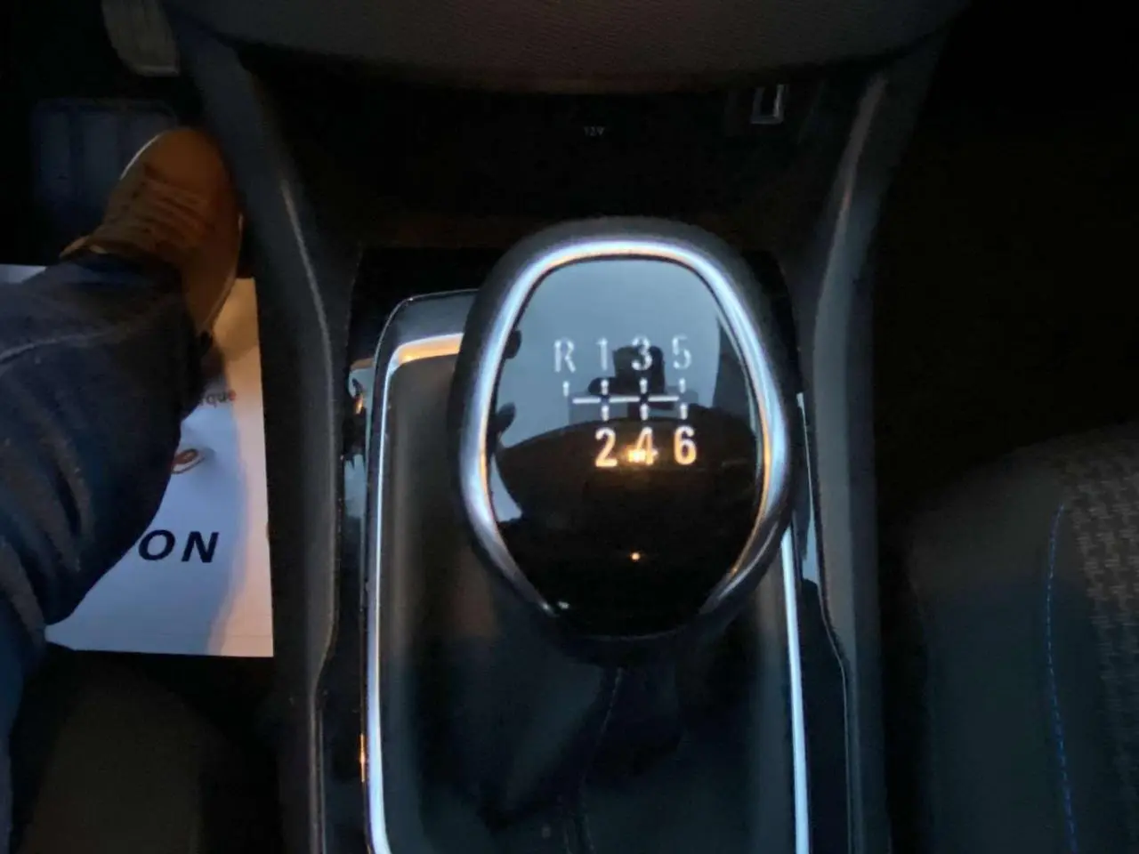 Gros plan sur le levier de vitesse manuel de la Peugeot 308 gris clair, avec indications des 6 rapports et marche arrière.