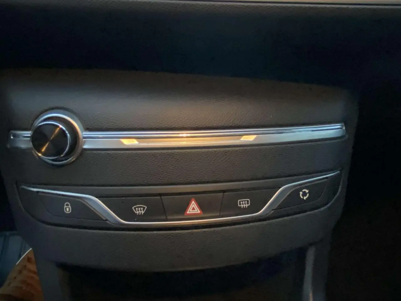 Gros plan sur la console centrale noire de la Peugeot 308 2020 avec boutons de verrouillage, warning et dégivrage.