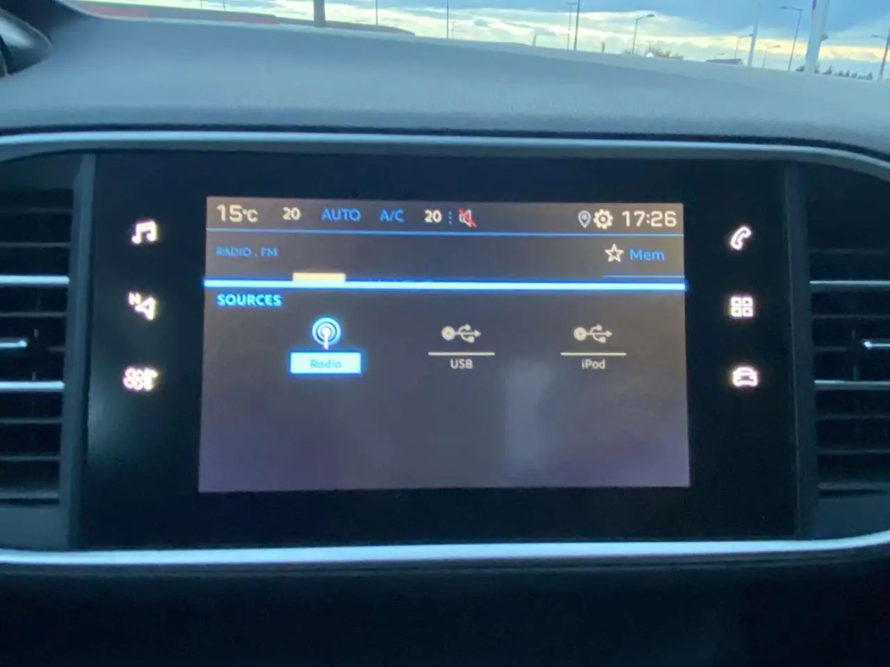 Écran tactile central de la Peugeot 308 2020 affichant les sources audio avec commandes lumineuses autour.