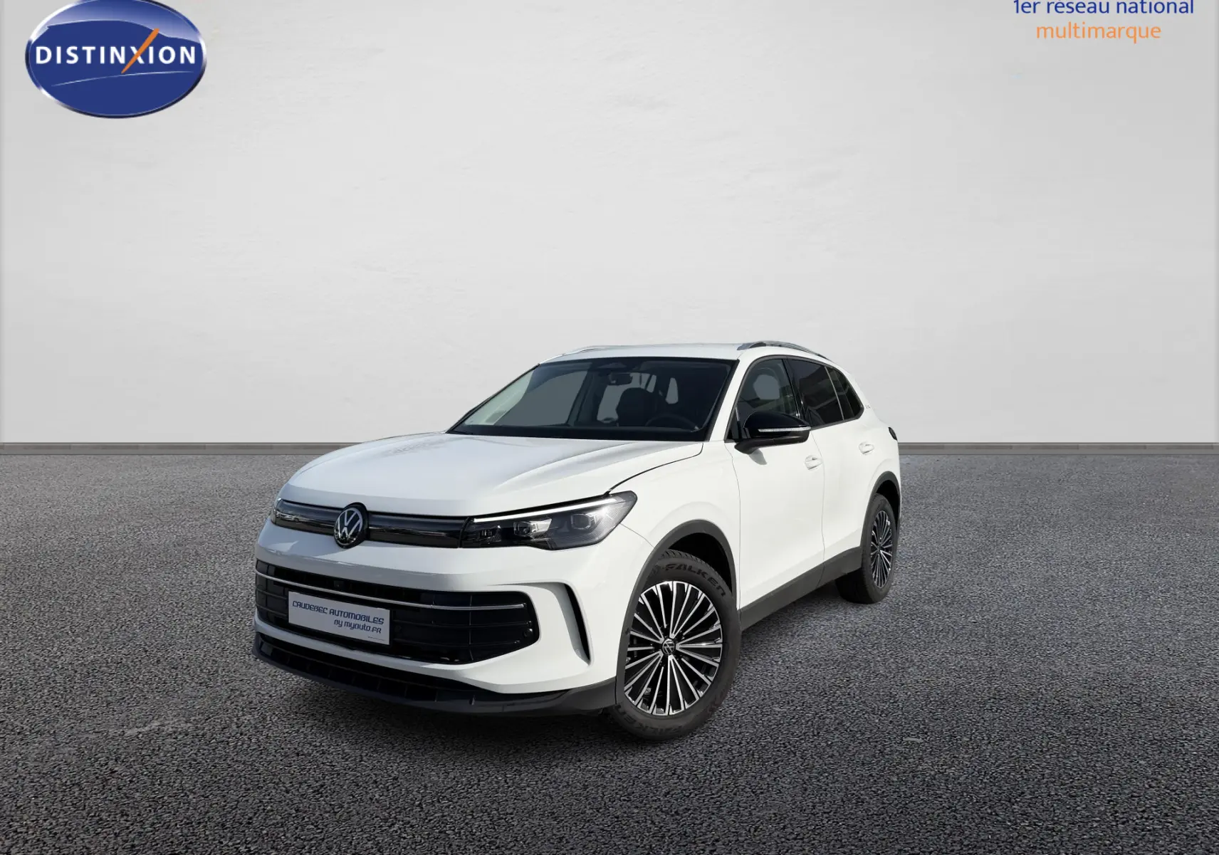 Volkswagen Tiguan blanc en 3/4 avant droit, avec jantes alliage noir brillant, devant un concessionnaire.