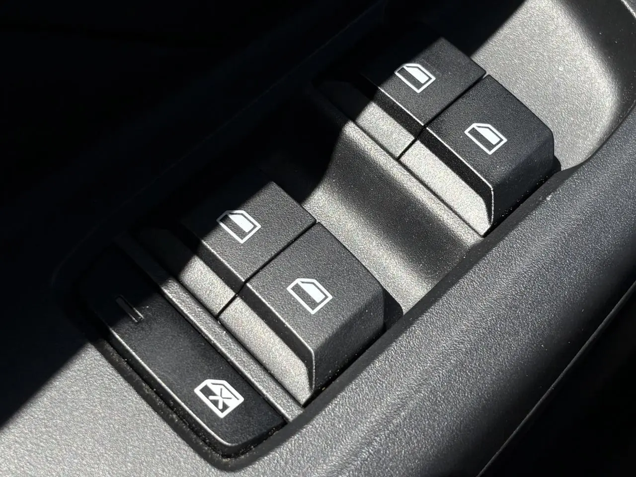 Gros plan sur les boutons de commande des vitres électriques côté conducteur du MG3 blanc Dover 2025.