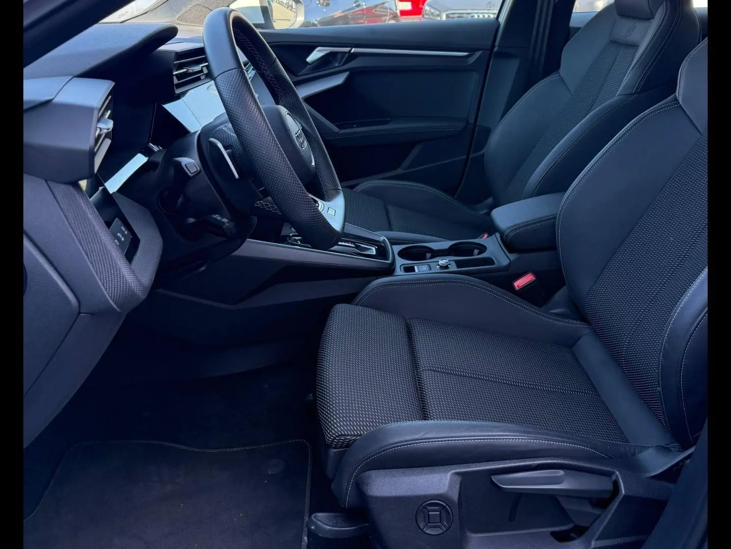 Intérieur avant droit de l’Audi A3 Sportback 40 TFSI e 2025 avec sièges sport noirs et volant cuir multifonction.