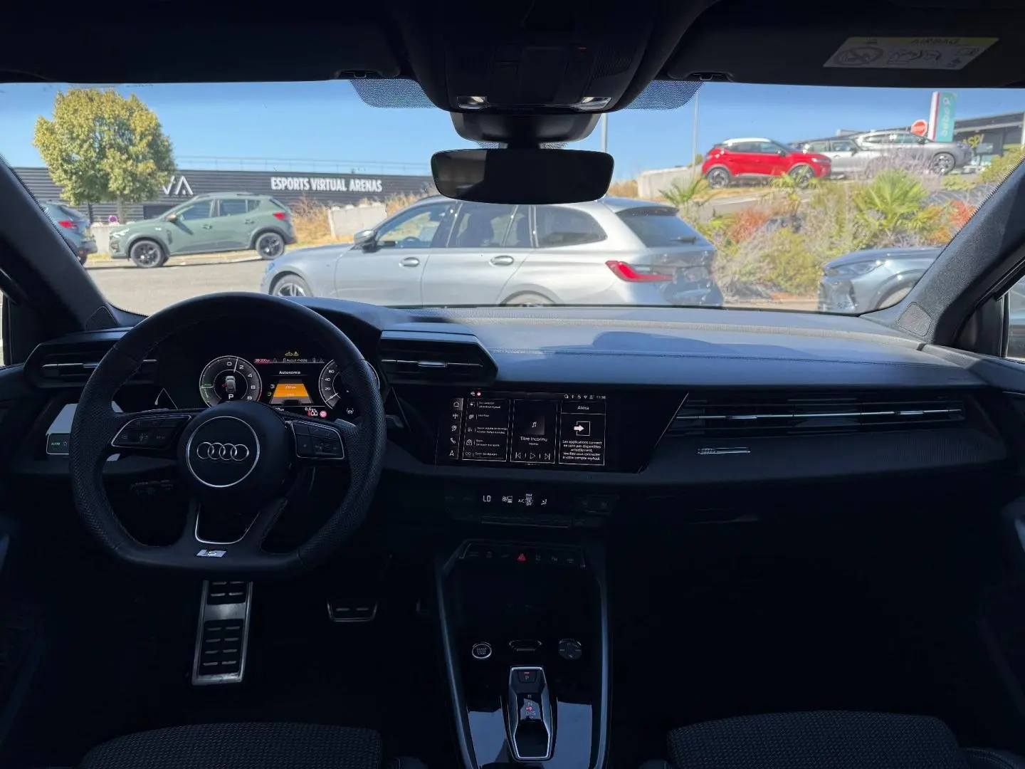 Vue intérieure avant de l'Audi A3 Sportback 2025, tableau de bord noir avec volant sport et écran digital.