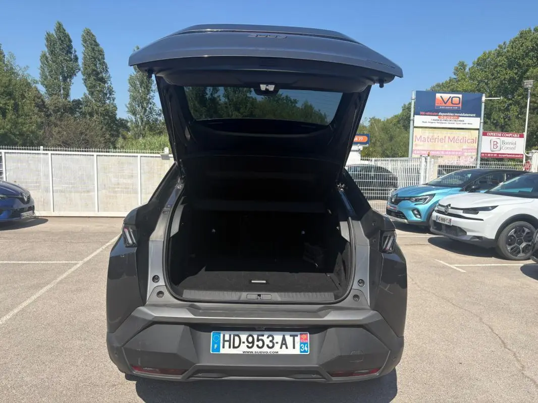 Vue arrière d'un Peugeot 3008 gris 2025 avec coffre ouvert, jantes alliage 18 pouces visibles au soleil.